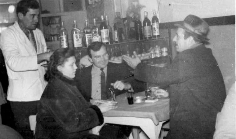 Crno-bela fotografija: konobar i gosti za stolom