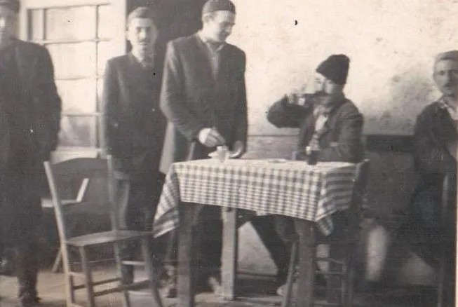 Stara fotografija u sepiji: gosti za stolom sa kariranim stolnjakom