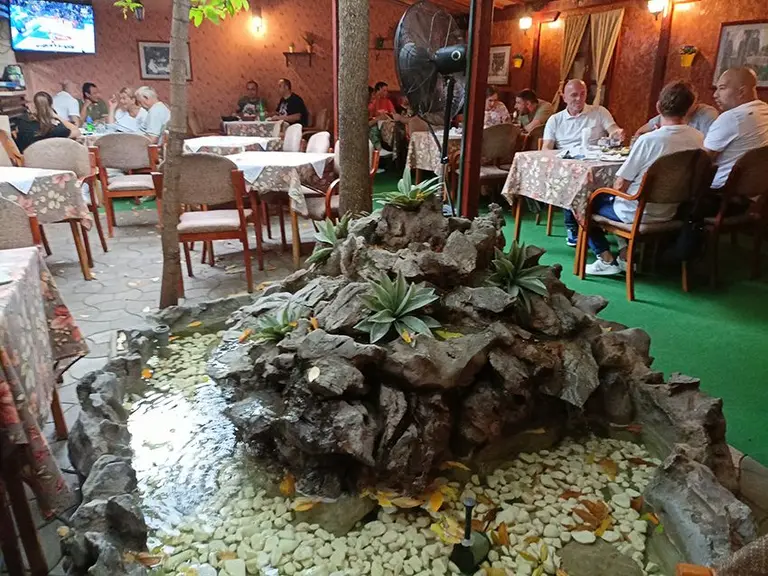 Bašta restorana sa gostima i fontanom