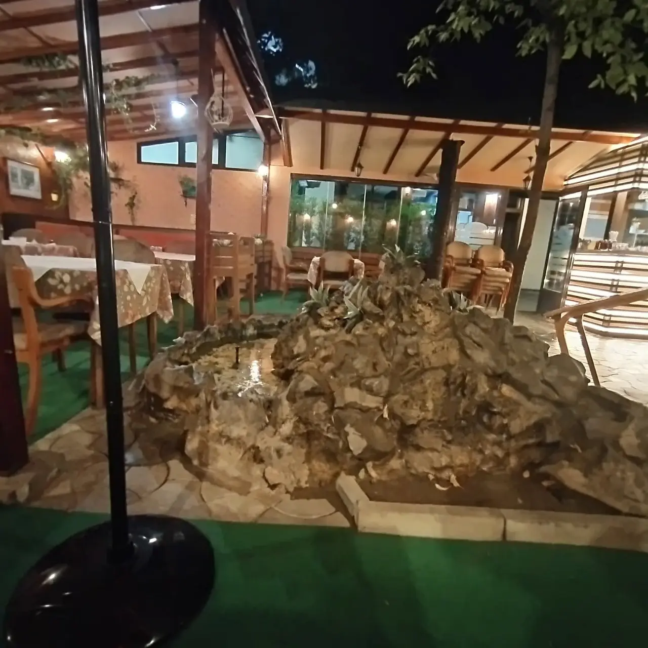 Bašta restorana uveče sa kamenom fontanom