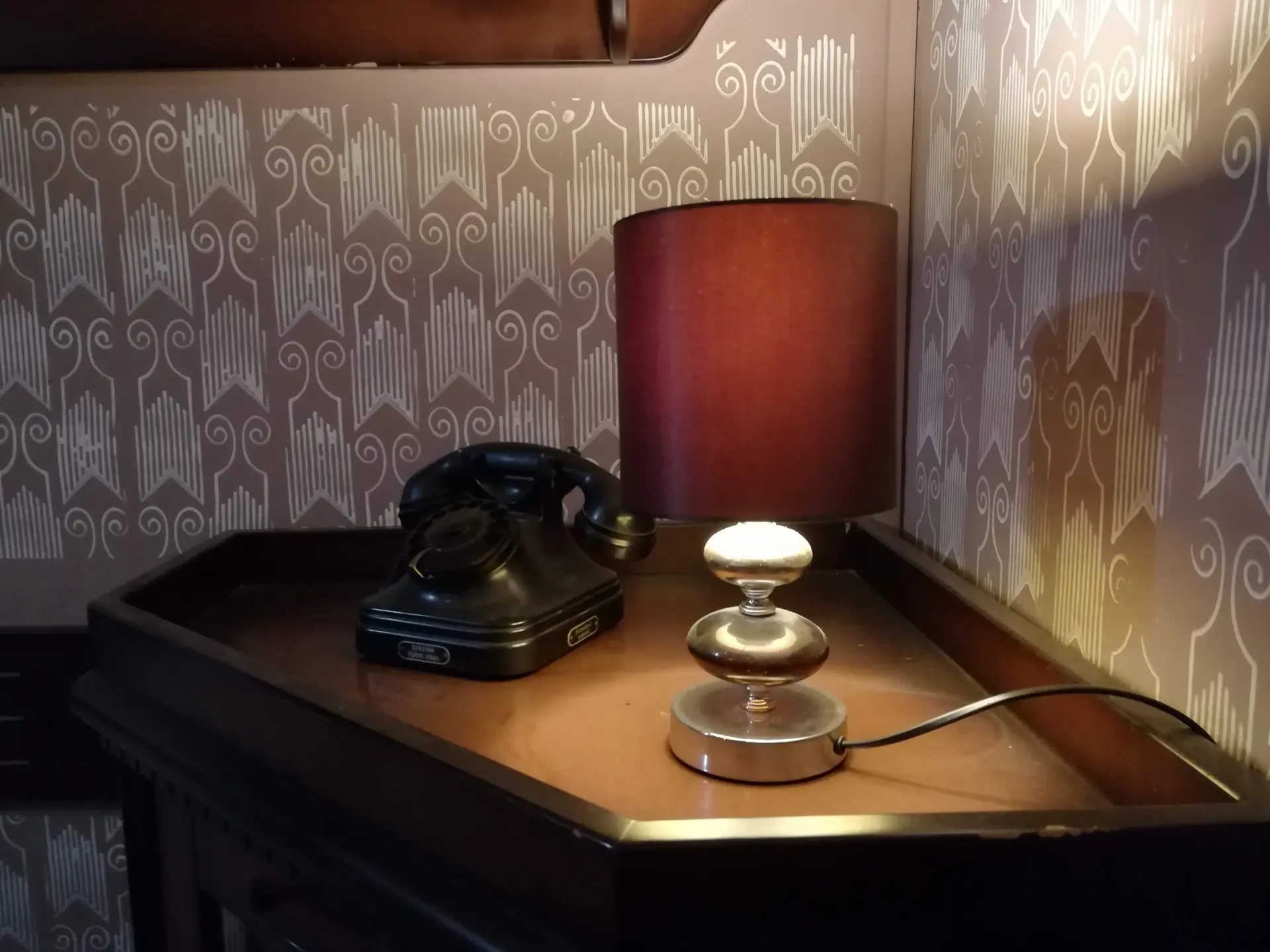 Stari telefon sa brojčanikom i stona lampa sa bordo abažurom