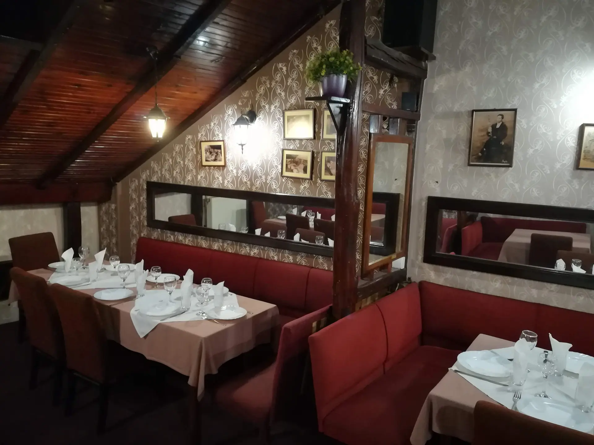 Sala pod kosim krovom sa crvenim klupama i starim fotografijama na zidu
