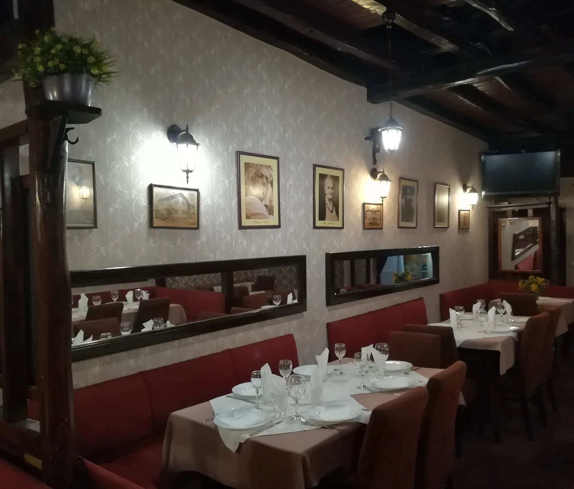Crvene klupe i postavljeni stolovi uz zid sa starim portretima i ogledalima