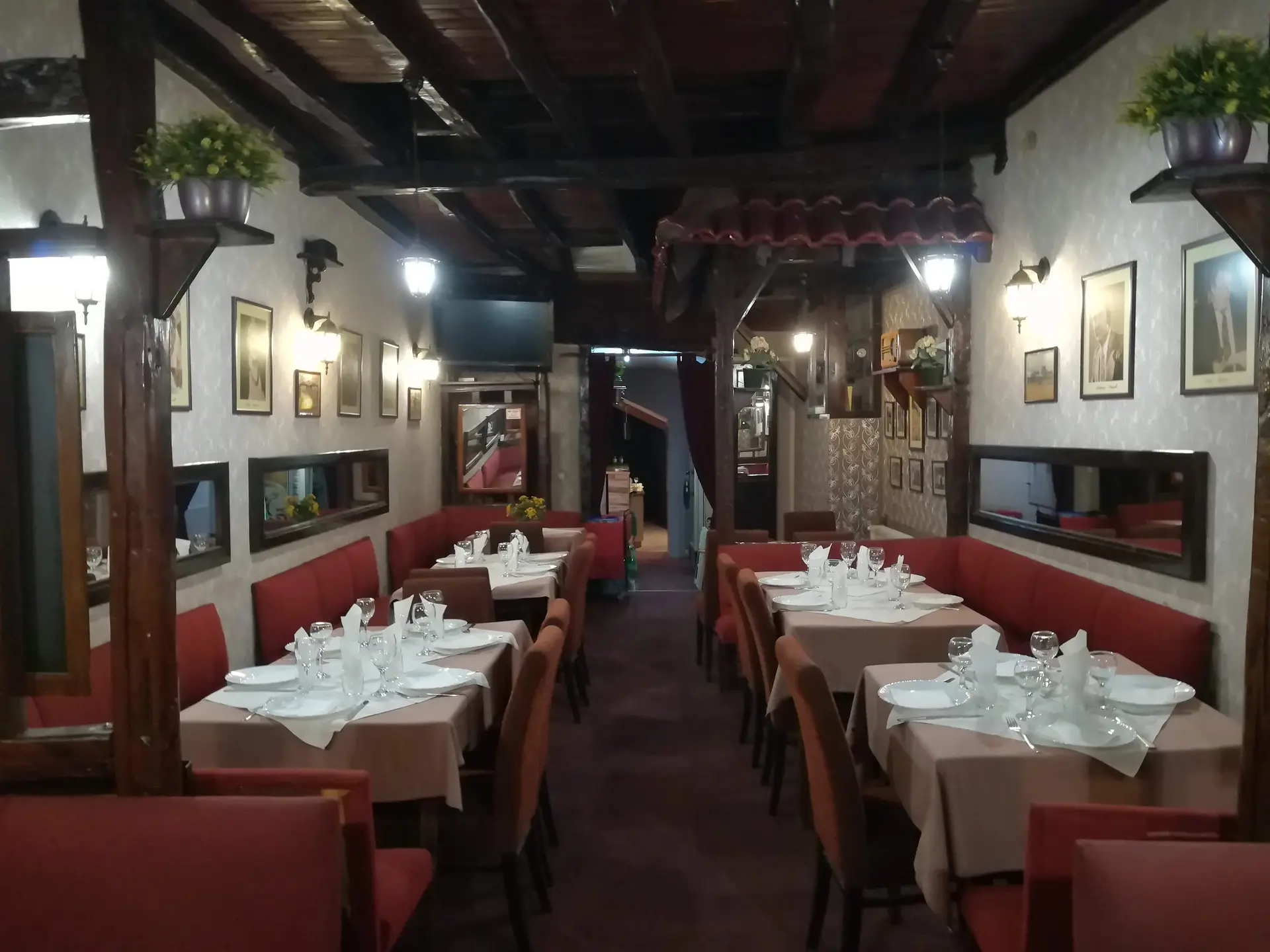 Stari deo restorana sa drvenim gredama, crvenim klupama i postavljenim stolovima