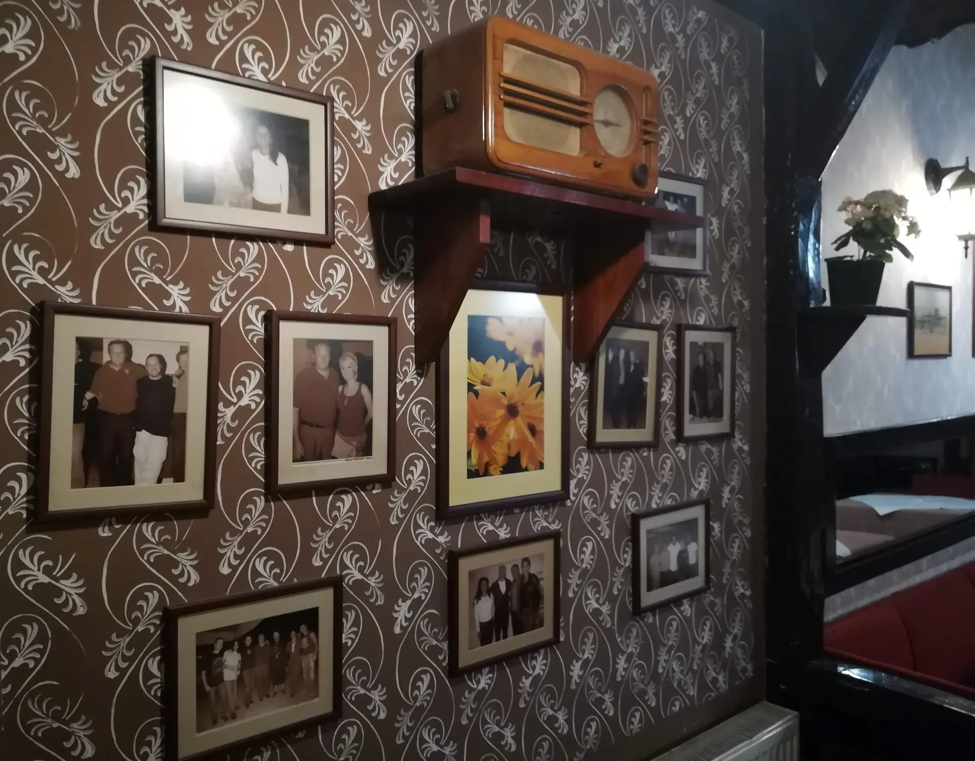 Zid sa uramljenim fotografijama i starim drvenim radiom
